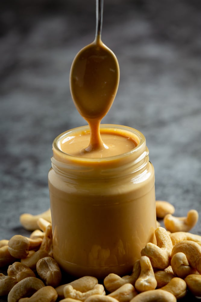 A creamy swirl of rich, golden peanut butter in a cup, smooth and ready to be used in a delicious recipe.